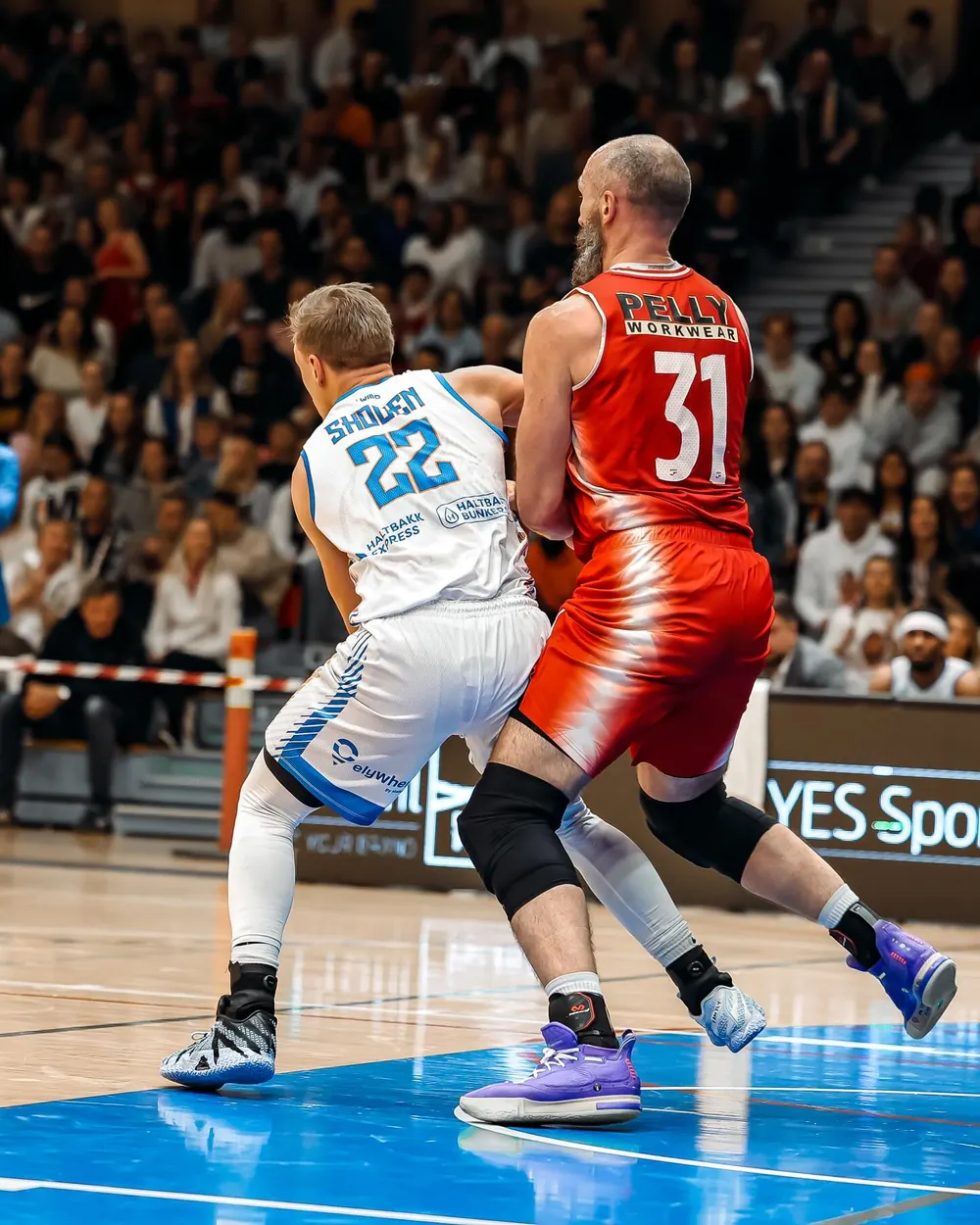 Nikolas wearing number 22 with Skouen on his back, battling in front of a full crowd
